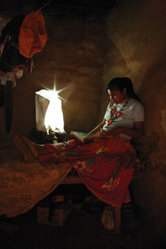 A Huichol woman reads by the light from her “portable light” bag